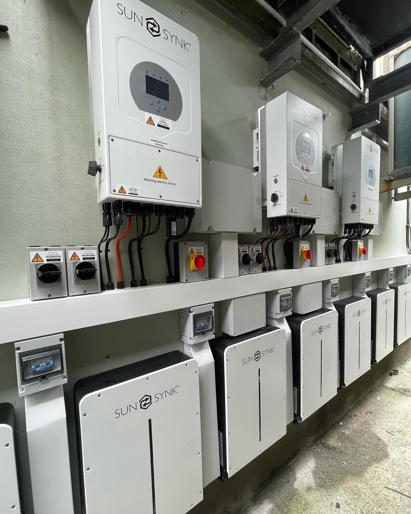 Multiple SunSynk inverters and battery modules installed in a commercial plant room