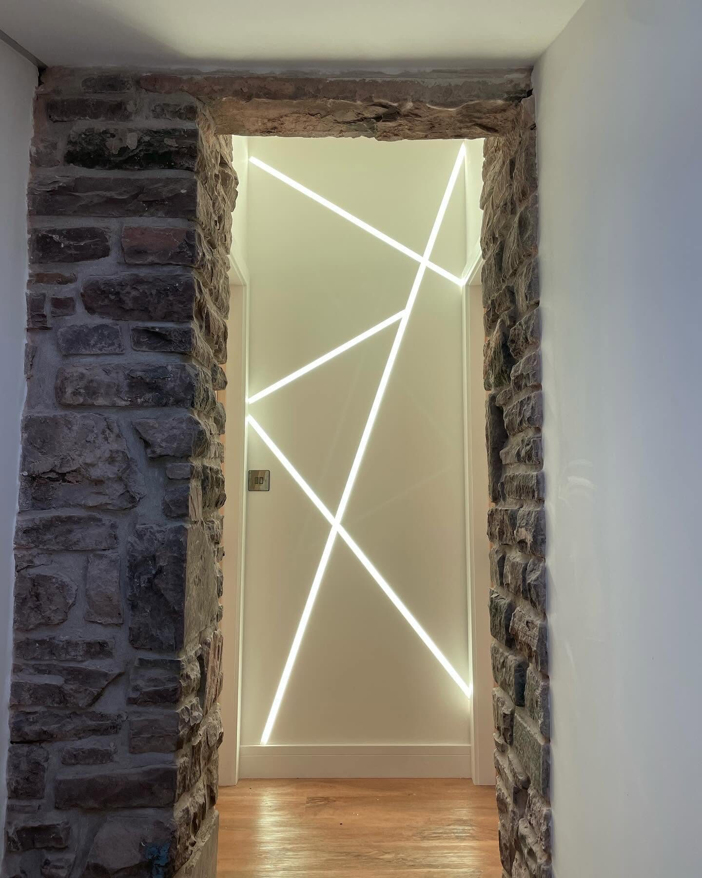 Linear feature lighting installed around a stone-framed doorway