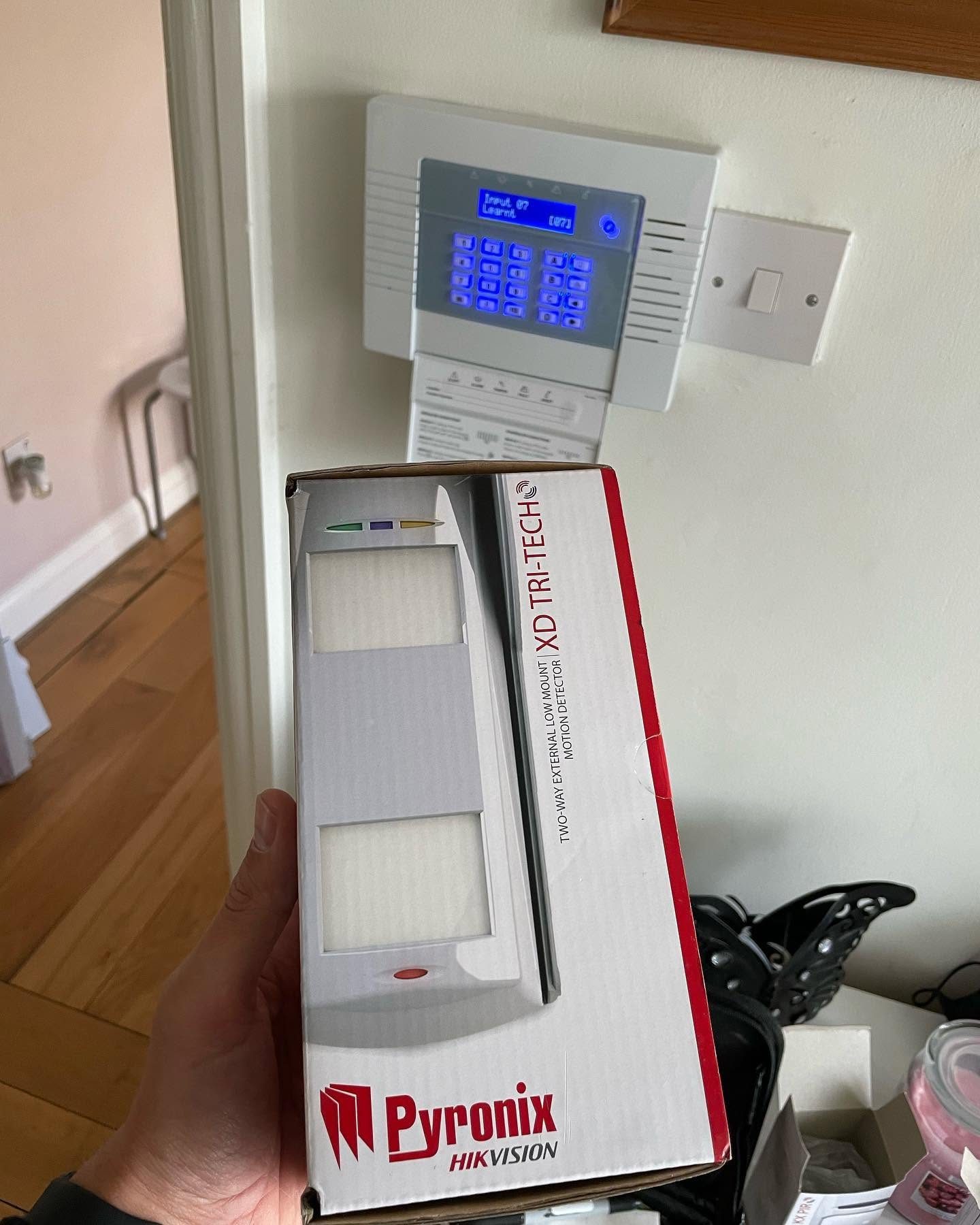 Pyronix Hikvision motion detector held in front of a newly fitted alarm keypad