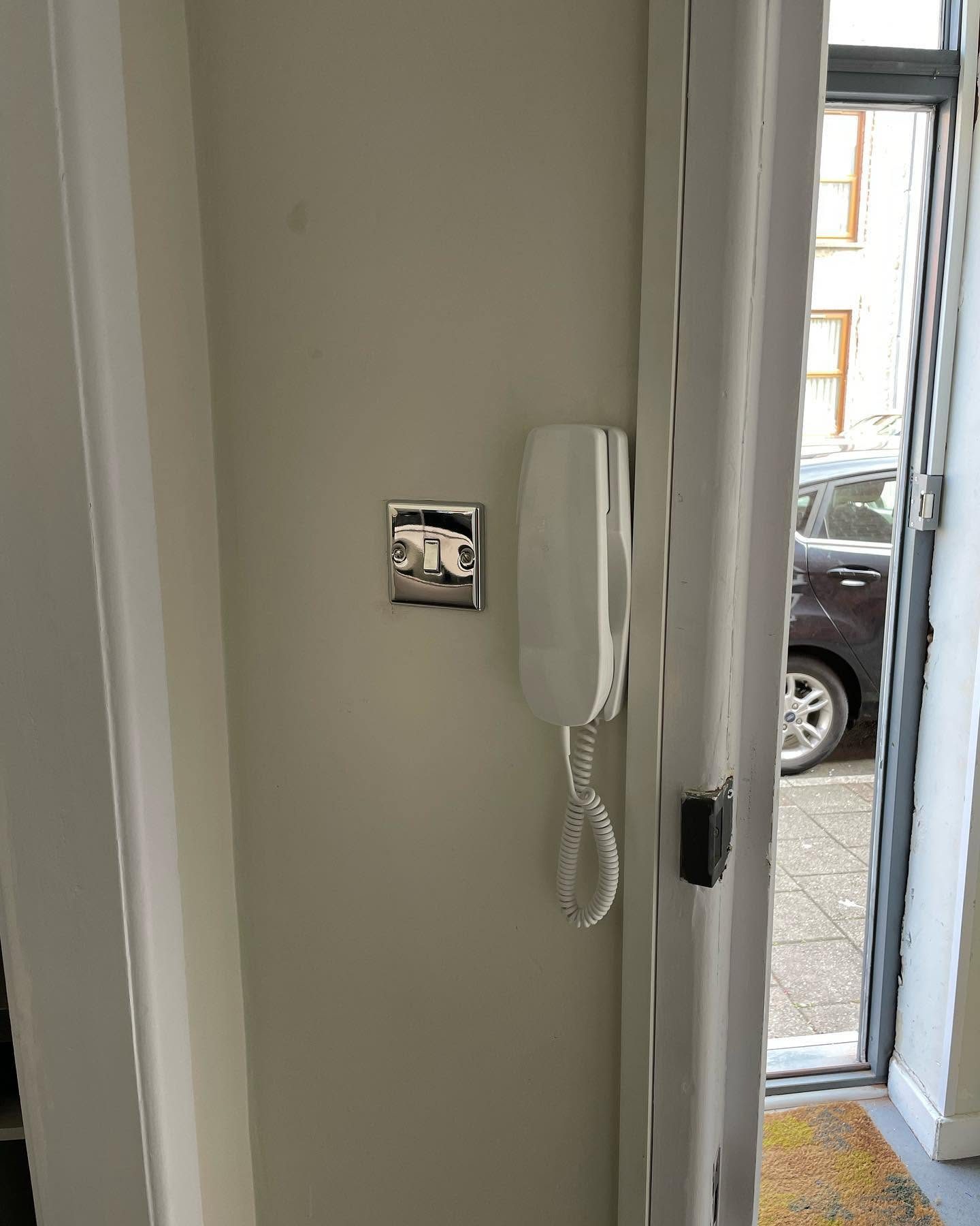 Wall-mounted intercom handset installed beside an internal doorway