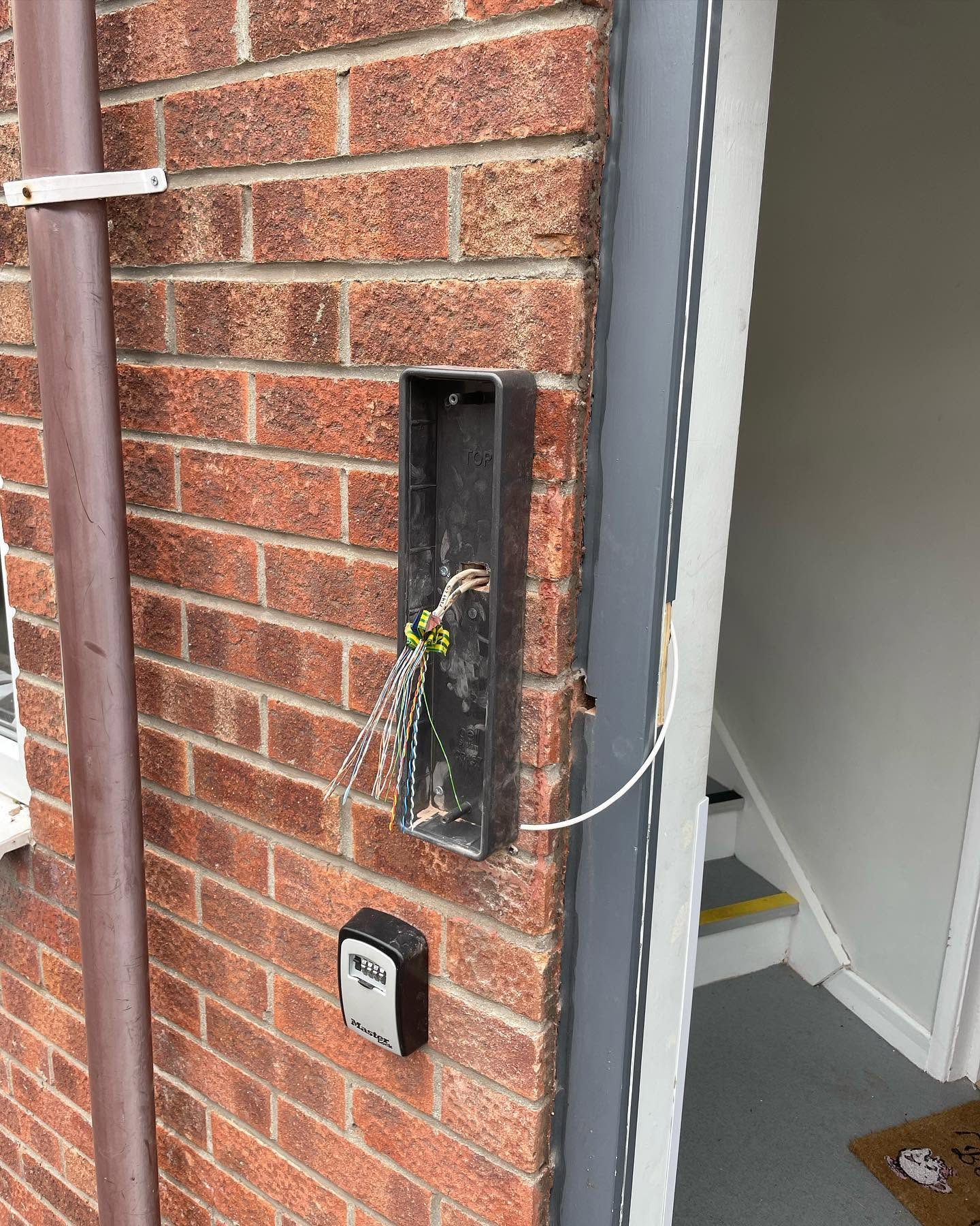 Alarm cabling enclosure and key safe installed on an exterior brick wall