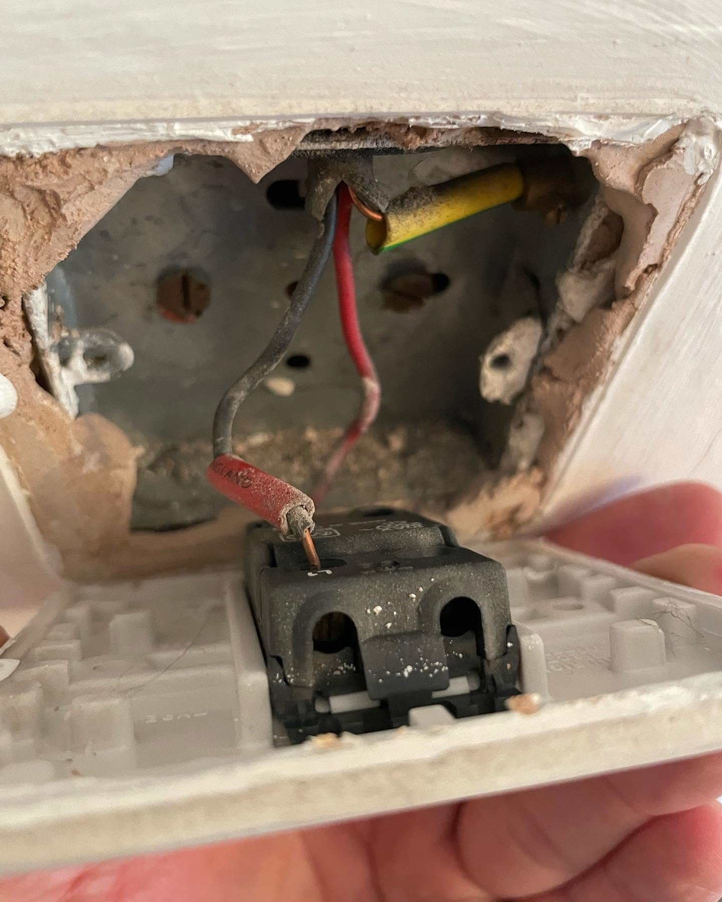 Damaged socket outlet and back box exposed during electrical repair work