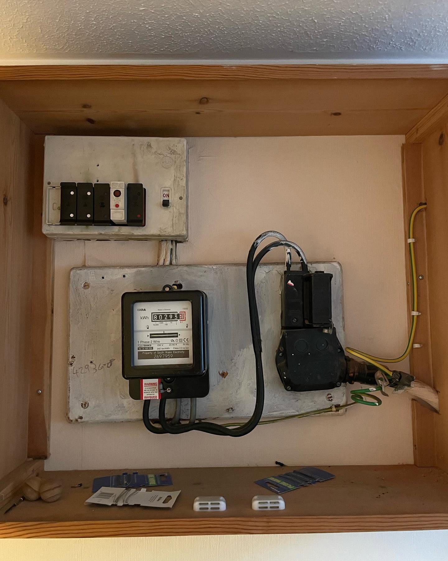 Older electricity meter and switchgear inspected inside a meter cupboard
