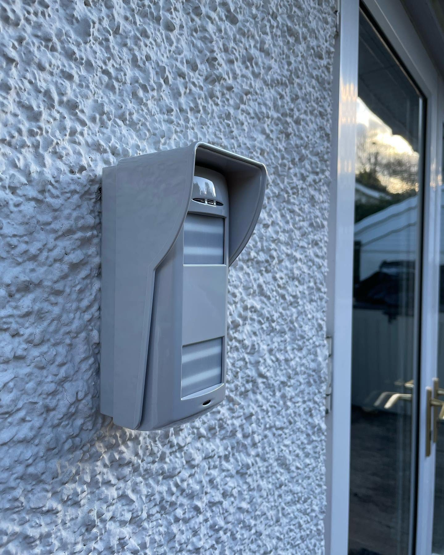 External wall-mounted security detector fitted beside a glazed door