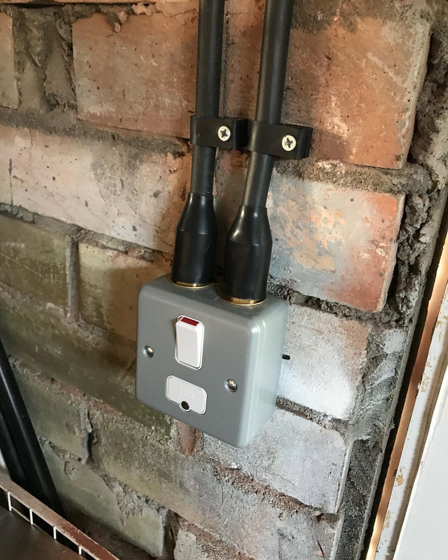 External weatherproof fused switch and conduit installed on a brick wall