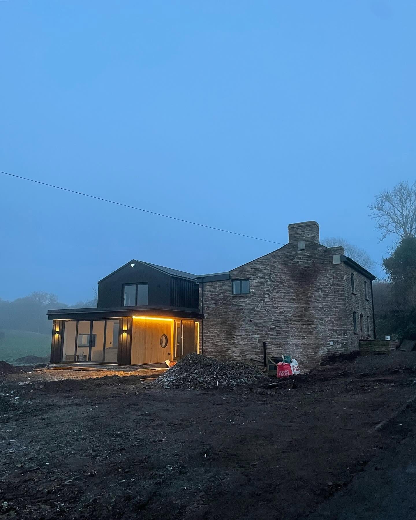 Exterior lighting on a stone house renovation photographed at dusk