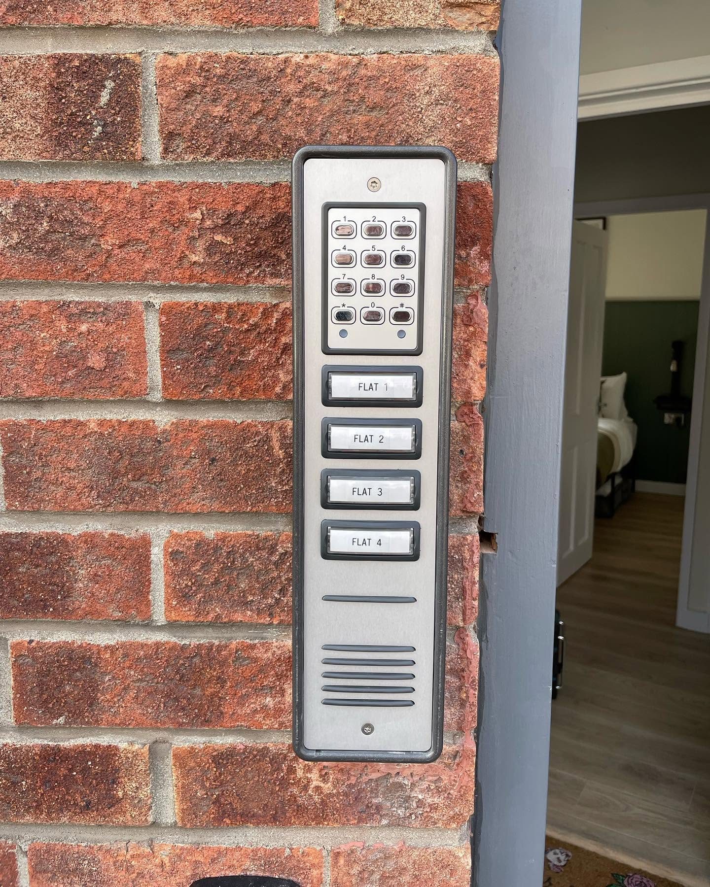Stainless steel door entry keypad and intercom panel serving four flats